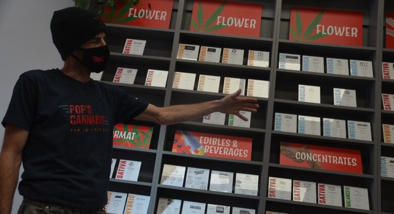 A man, Jamy McKenzie, displays cannabis products on the shelf of a store in Sudbury.