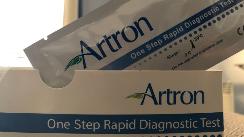 A COVID rapid test sits on top of the box. It is branded Artron.