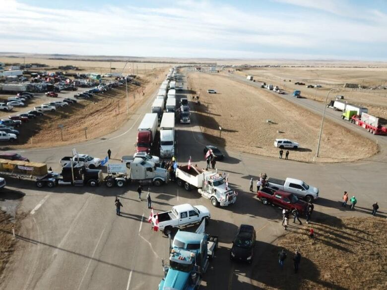 A long line of semi trucks lineup down a highway.