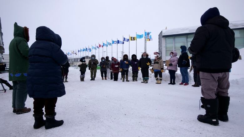 People stand outside in a circle facing each other 