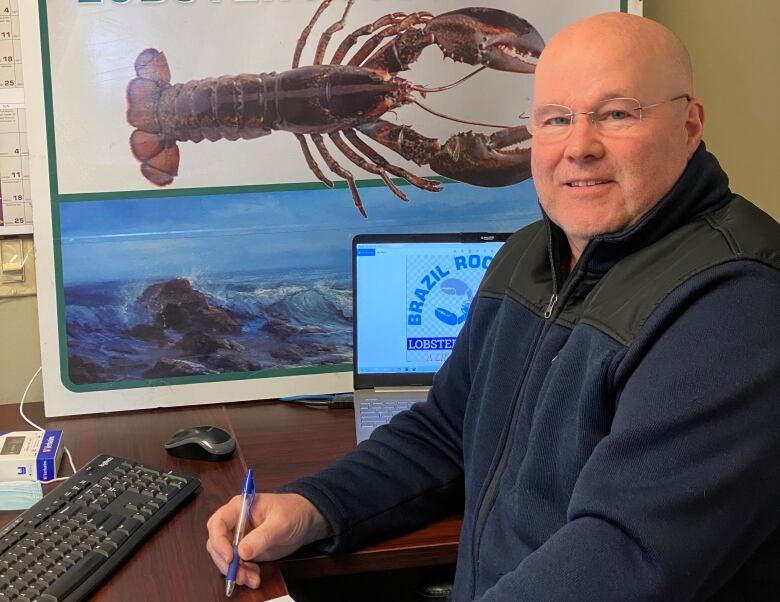 A bald man with glasses sitting at a desk.