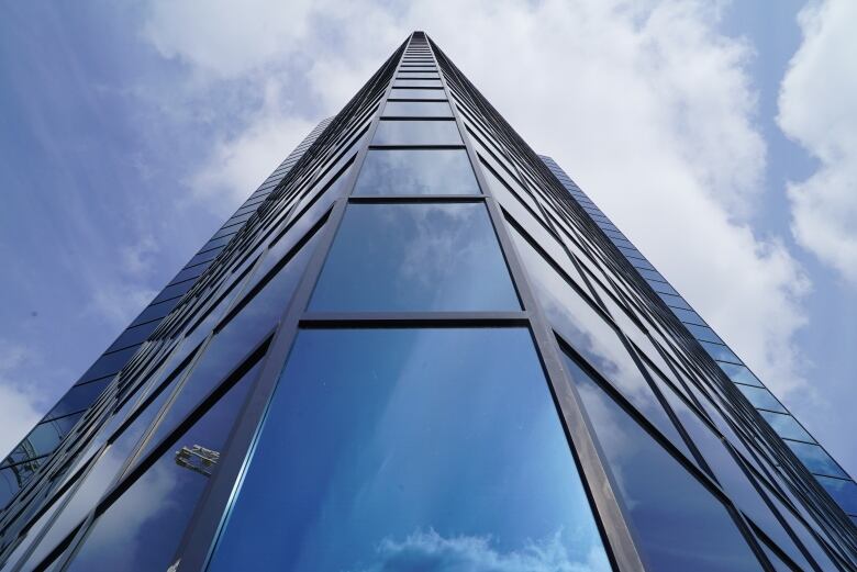 A glass office tower is shown against a blue sky.