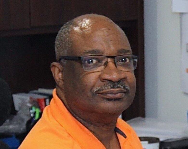 A Black man wearing glasses and an orange shirt