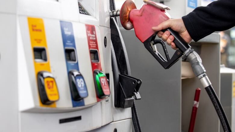 A gas pump with a hand on the handle