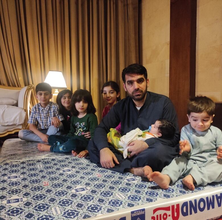 Mohammad Nasimi and his children pose in the hotel room in Islamabad where they're staying, until they can move to Canada. 