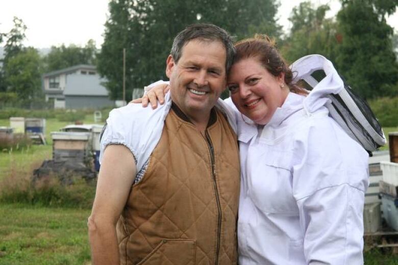 Husband and wife in beekeeper outfit pose for a photo