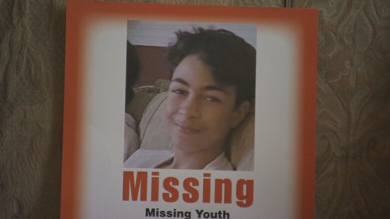 A photo of a boy is seen on a missing person poster.