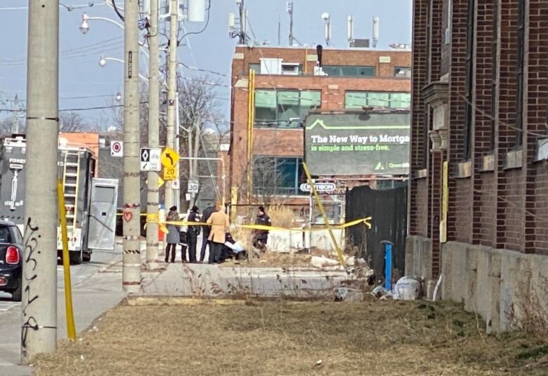 A crime scene on a street with caution tape surrounding it.