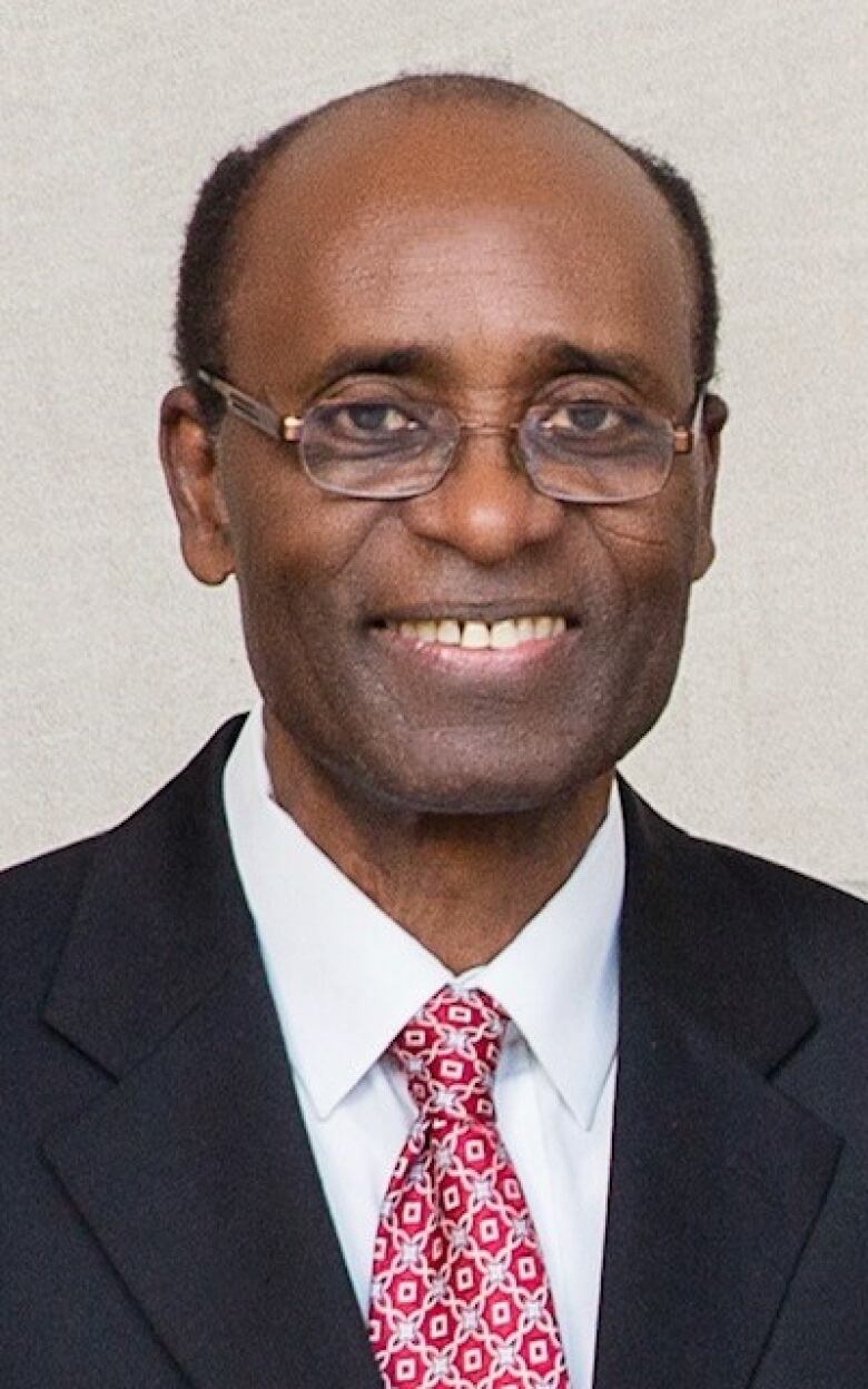 A Black man wearing a black suit and red tie