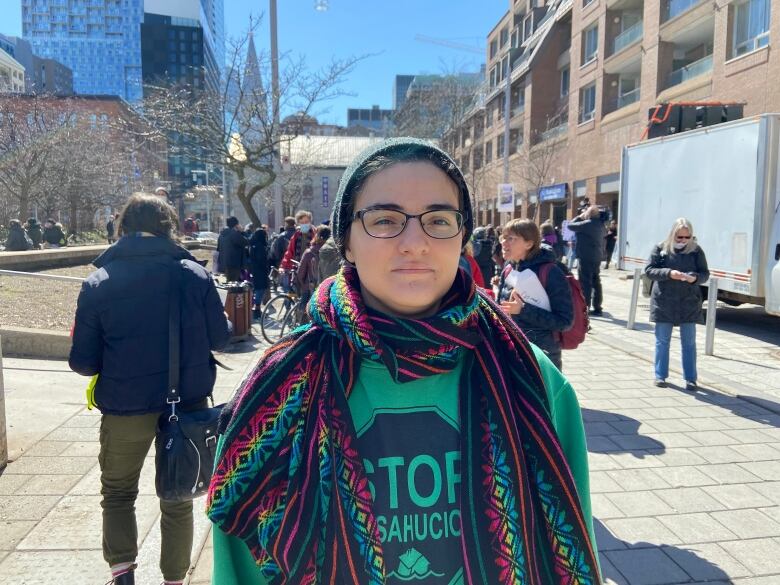 woman with glasses in green sweater and colourful scarf looking at the camera