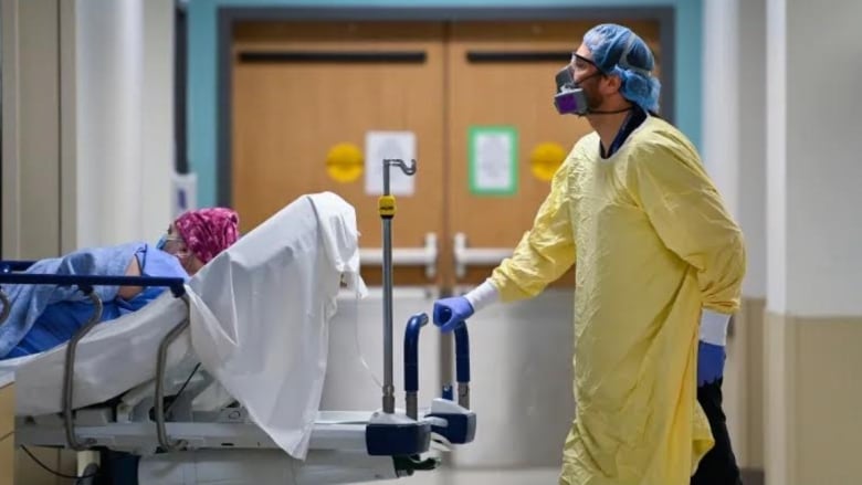 Masked doctor pushing patient in hospital.