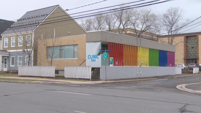 A one-storey building on a street corner with a sidewall painted in rainbow colours. A sign says Clinic 554.