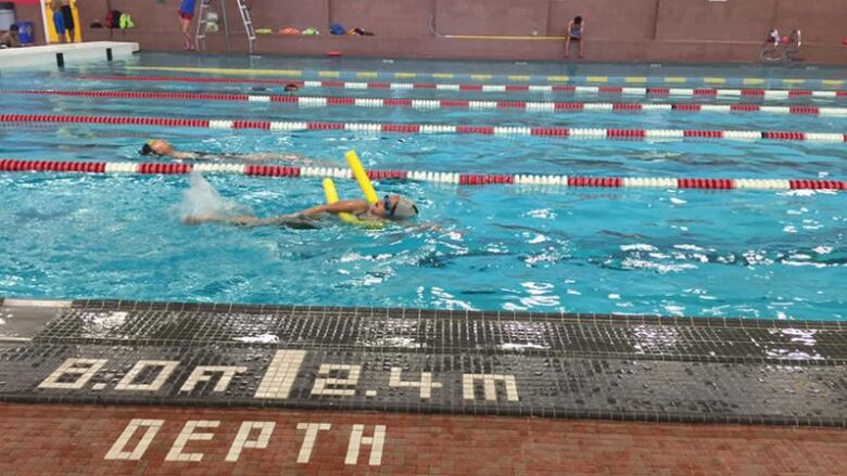 People swim laps in an indoor pool.