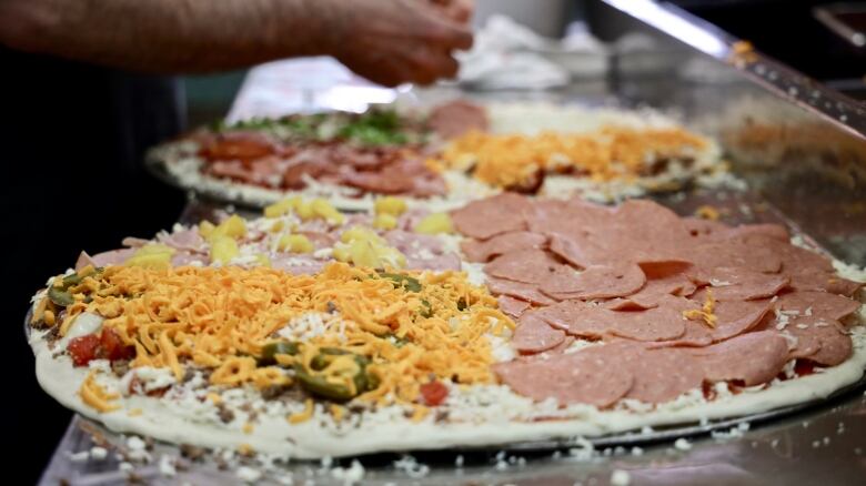 Two unbaked pizzas with various toppings visible on them.