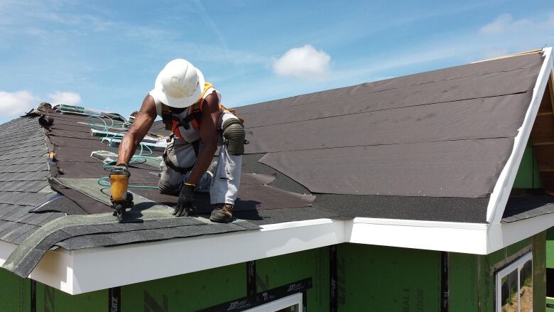 A construction worker does roofing on top of a newly built home.