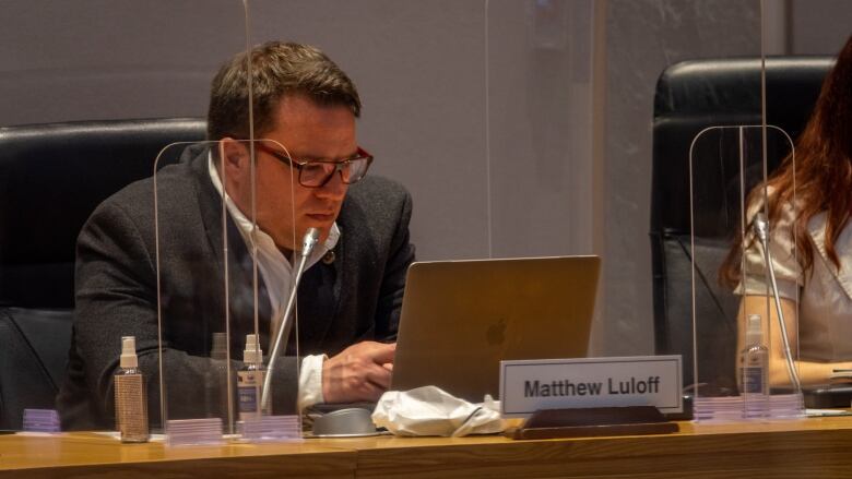 A city councillor sits at a meeting.