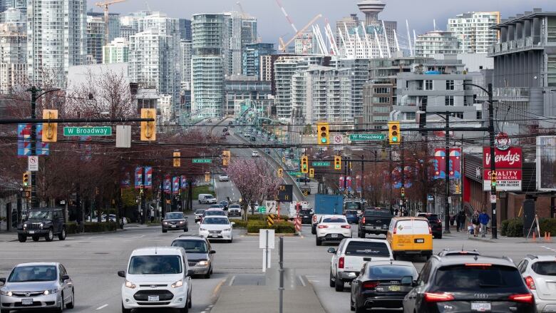 Cars are pictured on a busy road against the Vancouver skyline.