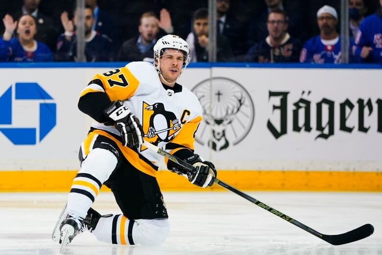 A hockey player kneeling on the ice in a Pittsburgh Penguins uniform