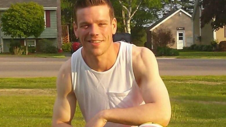 Picture of a smiling young man in a white tank top.