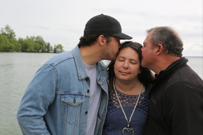 Cheryl-Anne Labrador-Summers' husband and one of her sons kiss her on the dock near their lakeside home in Georgina, Ont.