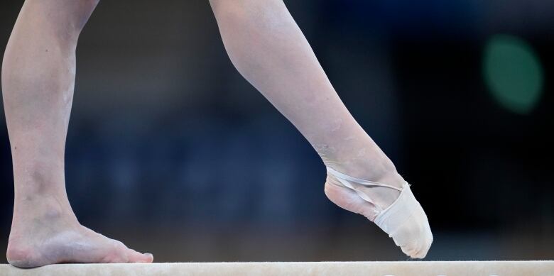 A gymnasts legs are seen on a balance beam.