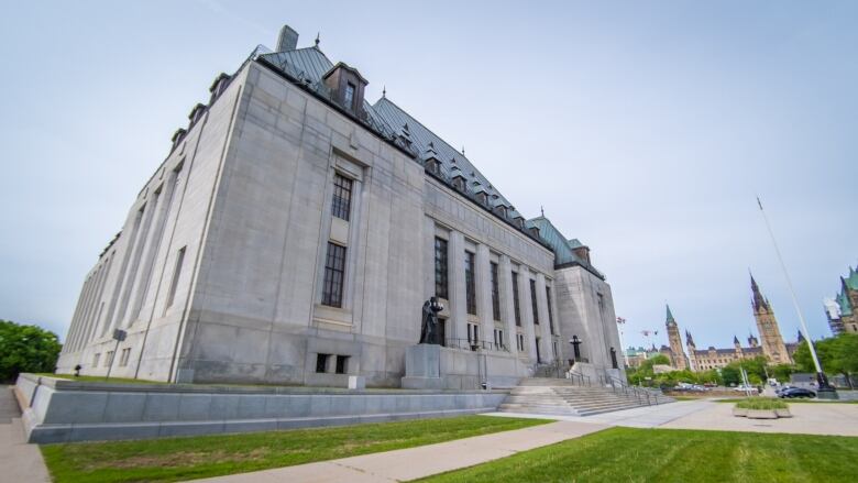 The outside of the Supreme Court of Canada in Ottawa with the Parliament Buildings in the background 