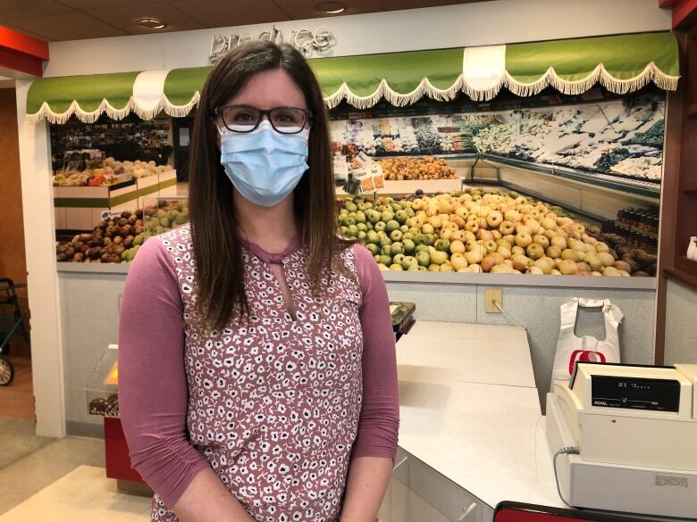 A woman in a mask looks at the camera.