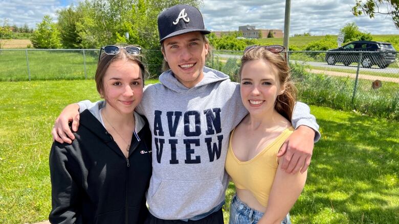 Three students of Avon View High School are seen smiling outside together. 