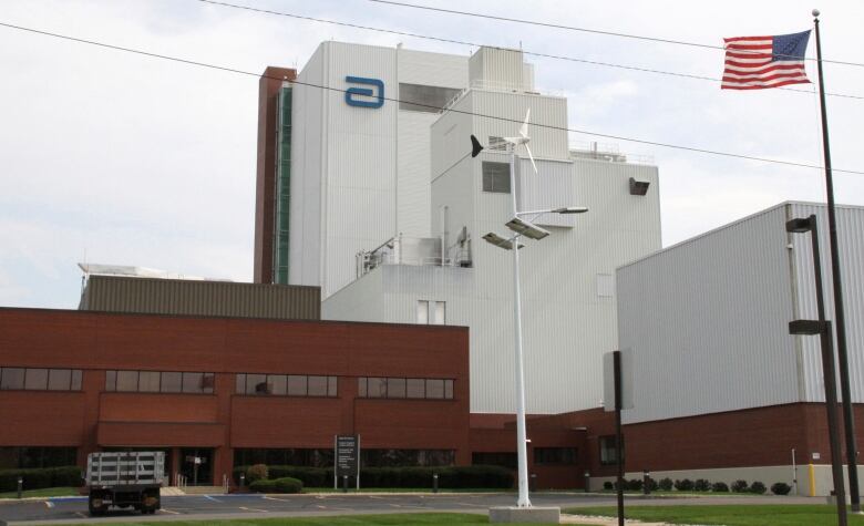 A brick building, combined with a white building, and an American flag out front.