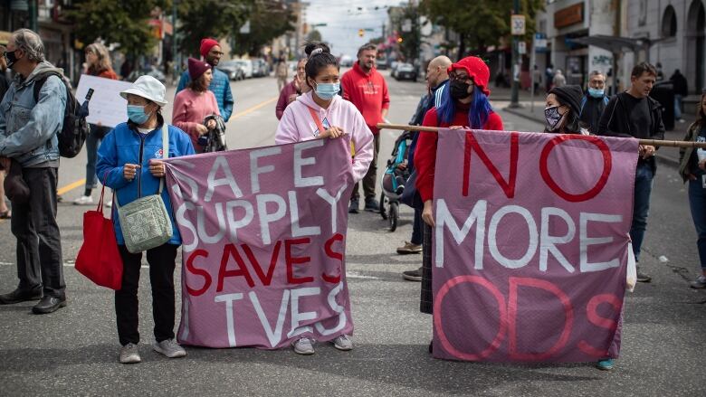 People hold banners during a march to remember those who died during the overdose crisis and to call for a safe supply of illicit drugs on International Overdose Awareness Day, in Vancouver, on Tuesday, August 31, 2021.