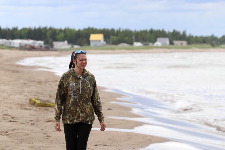 A woman walking along a windy beach. 