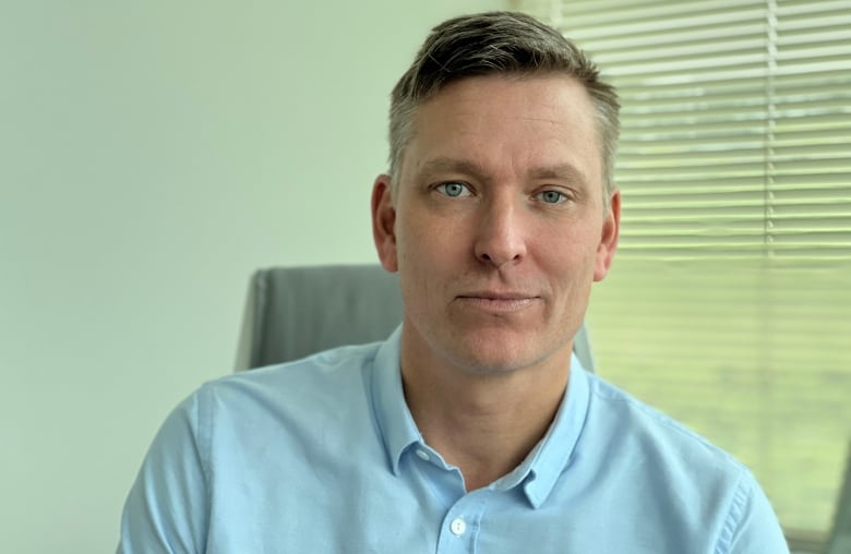 A man in a blue shirt sits in an office.