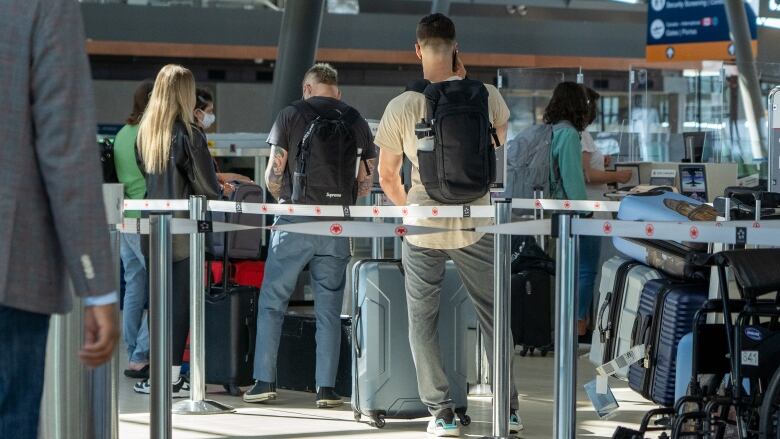 Travellers line up with their bags at an Ottawa International Airport counter June 14, 2022.