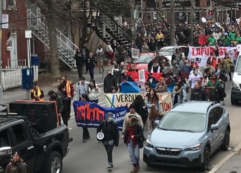 Protesters walk down a street in Montreal's Verdun borough holding banners in support of affordable housing and tenant rights.