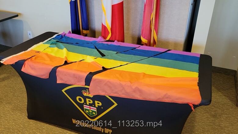 A rainbow flag is laid out on a black table. It has been cut into six pieces. 