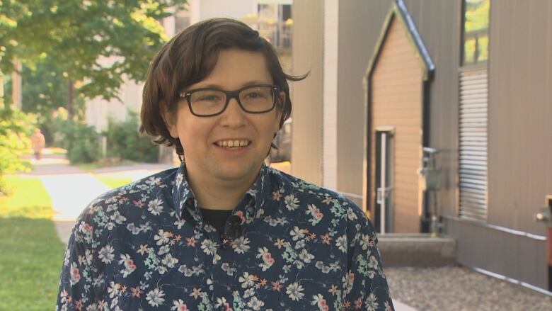 A young person wearing glasses speaks to a reporter. 