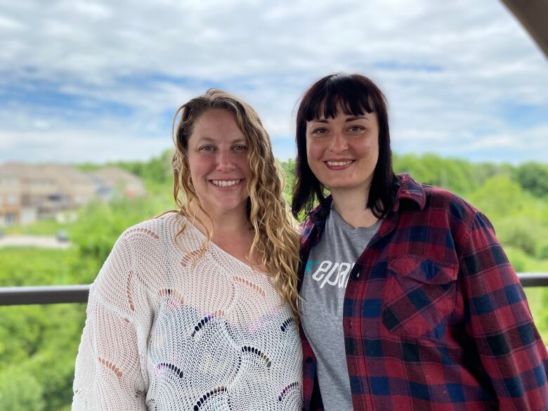 Two women pictured side by side on an outdoor patio in a backyard.