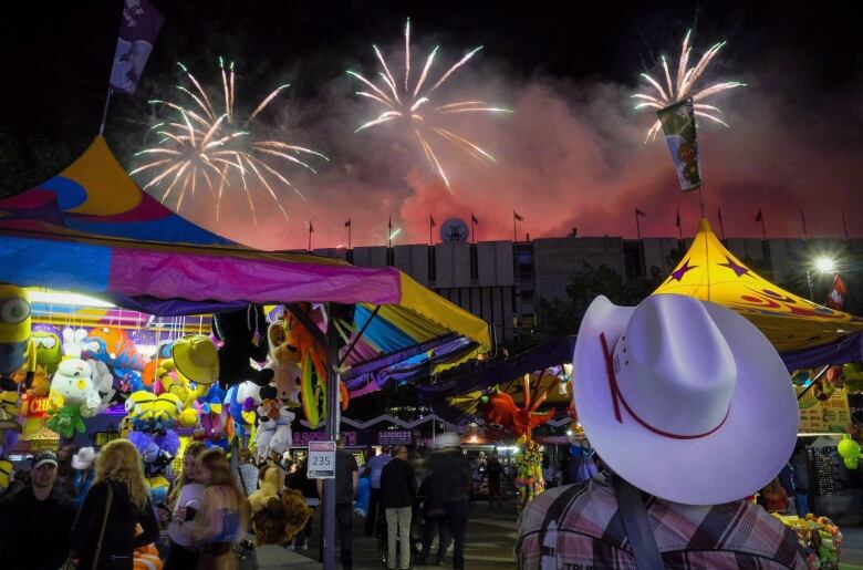 A visitor watches the fireworks display from the midway at the Calgary Stampede in Calgary, Saturday, July 9, 2016. The Stampede, which kicks off with a parade on July 7, is a time when the Calgary-based oilpatch puts on its cowboy boots and hosts pancake breakfasts, beer-soaked barbecues and corporate boxes at the rodeo and chuckwagon races.