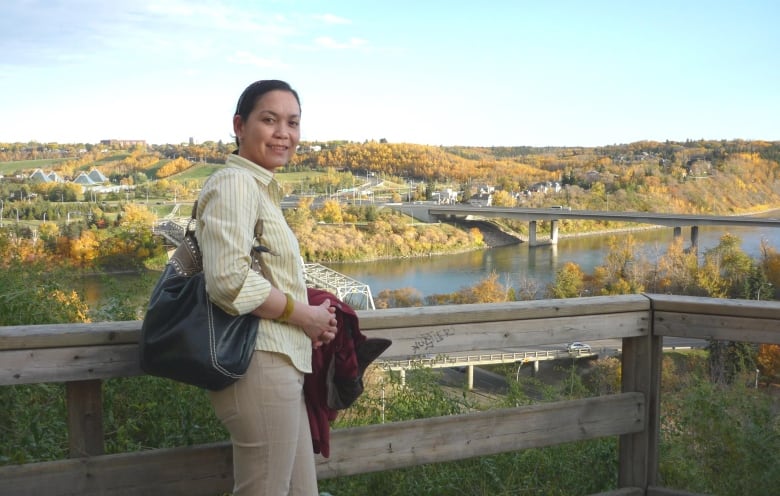 A Filipino woman poses with view of Edmonton river valley behind her.