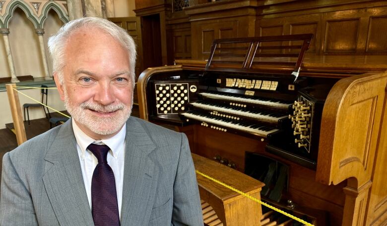 Man in suit seated at pipe organ.