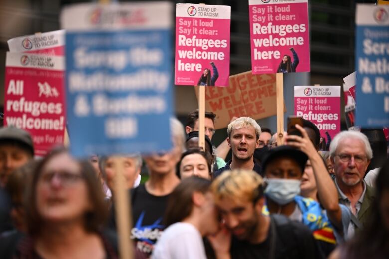 A crowd of people carrying protest signs bearing the words 