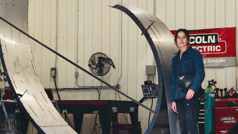 Woman stands beside large metal artwork created for Indigenous Peoples Day.