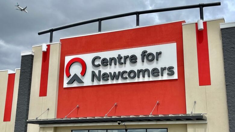 A building with a red sign that reads centre for newcomers.