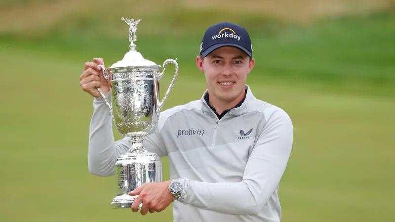 A young man holds a golfing trophy.