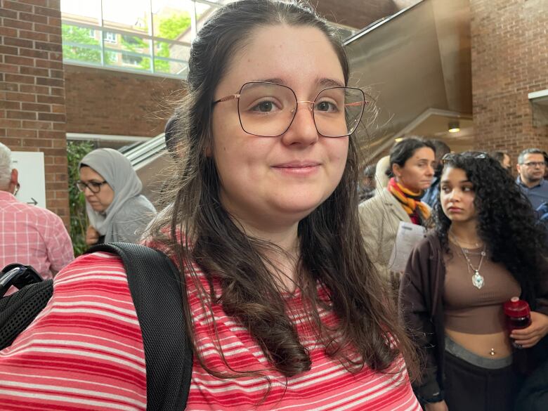 Frustrated-looking young woman in crowded lobby of a government building.