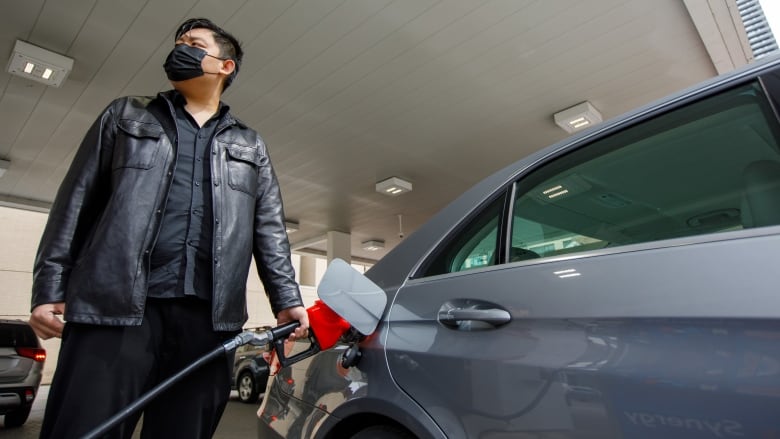 man in mask pumping gasoline