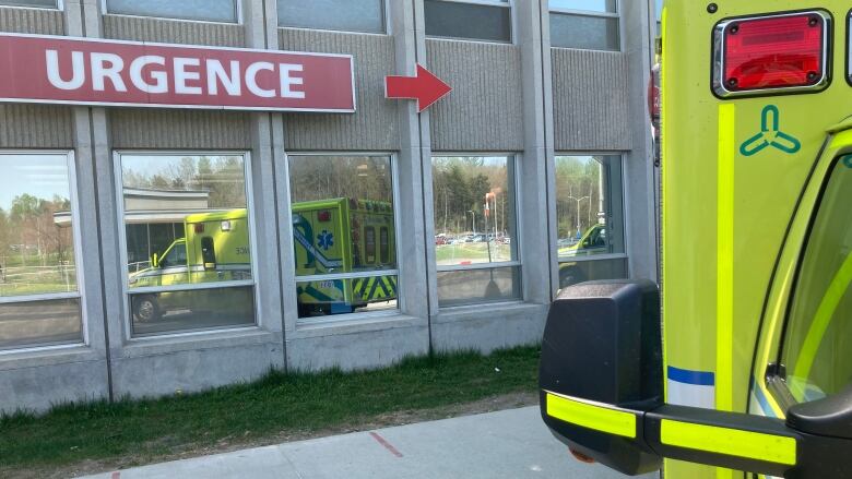 A sign that says 'Urgence' above windows where there is a reflection of an ambulance vehicle.