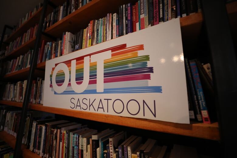 A full bookshelf is partially covered with a banner for OUTSaskatoon.