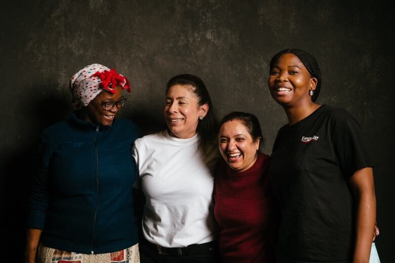 A portrait of four women smiling and hugging.