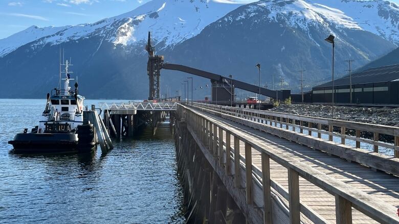 An industrial dock on the ocean with mountains visible across the water.